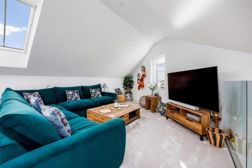 een woonkamer met een blauwe bank en een flatscreen-tv bij Dolce Vita - Duplex Apartment with Incredible Harbour Views in Poole