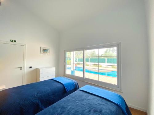 a bedroom with a bed and a large window at Villa Rio in Praia do Ribatejo