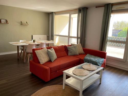 un salon avec un canapé rouge et une table dans l'établissement Le Duplex Convivial de Compiègne, à Compiègne