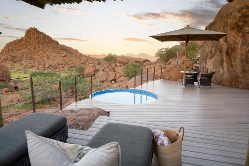 a deck with a couch and an umbrella and a pool at Mowani Mountain Camp in Khorixas