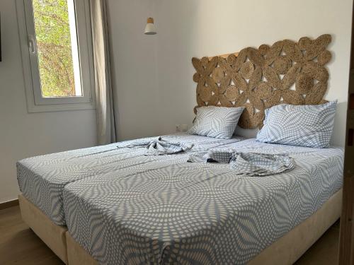 a bed with a blue and white comforter and a window at Garden Villa in Karpathos