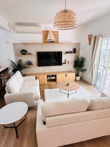 a living room with white furniture and a flat screen tv at Sands Beach LUX Villa Flic en Flac in Flic-en-Flac