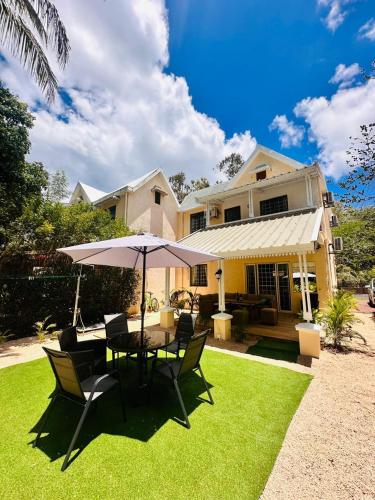 a table and chairs with an umbrella in front of a house at Sands Beach LUX Villa Flic en Flac in Flic-en-Flac