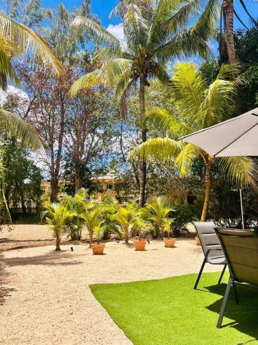 a beach with chairs and an umbrella and palm trees at Sands Beach LUX Villa Flic en Flac in Flic-en-Flac