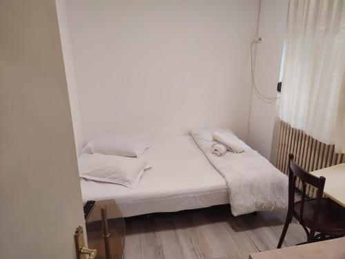 a small white bedroom with a bed and a chair at Iancu Apartments in Bucharest