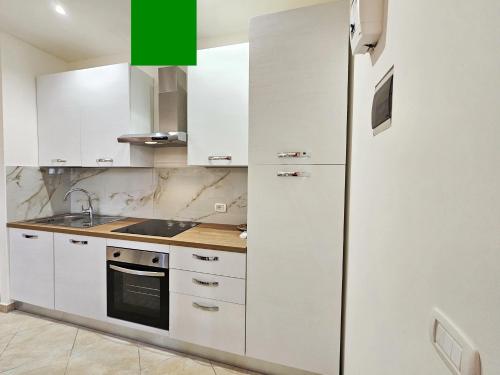 a kitchen with white cabinets and a refrigerator at Ariel Apartment Ortigia Siracusa in Siracusa