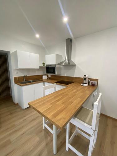 une cuisine avec une table en bois et des armoires blanches dans l'établissement Appartement cosy avec jardin, à Herrlisheim-près-Colmar