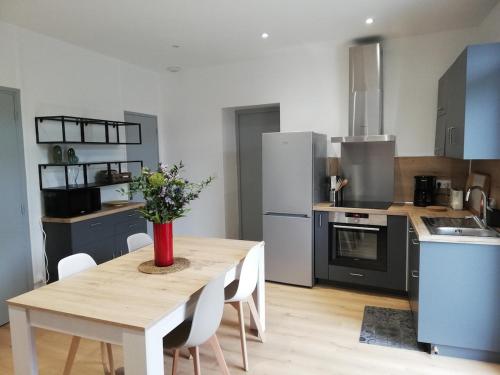 une cuisine avec une table en bois et un vase de fleurs. dans l'établissement Gîte Lou Cagnard au coeur des gorges de l'Ardèche, à Saint Alban Auriolles