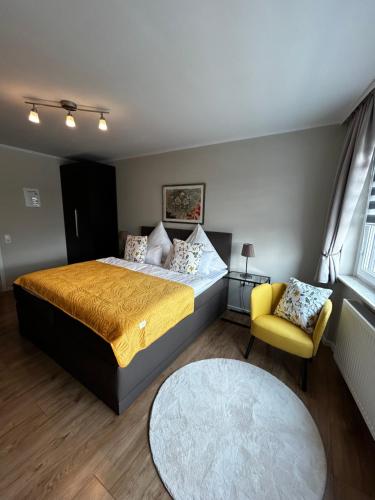 a bedroom with a bed and a yellow chair at WohnRaum Gäste- & Boardinghaus in Gusterath