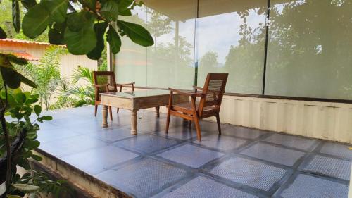 a patio with two chairs and a table on a porch at Vanaswara in Kolād