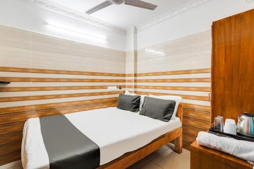 Un dormitorio con una cama con una pared de madera. en Super Hotel O Sharmila Guest House, en Pondicherry