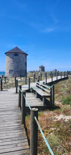 a wooden boardwalk leading to a building on the beach at Salgueira Pilgrim's Rest in Apúlia
