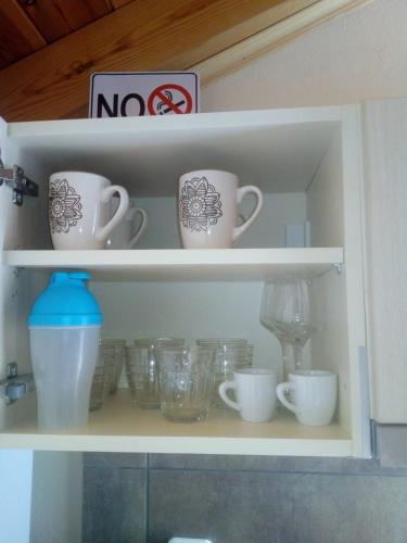 a cupboard filled with cups and bowls at Maria's Sea View Apartments in Mousata