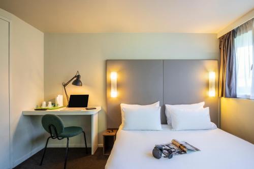 a hotel room with a bed with a desk and a laptop at Campanile Auxerre - Monéteau in Monéteau