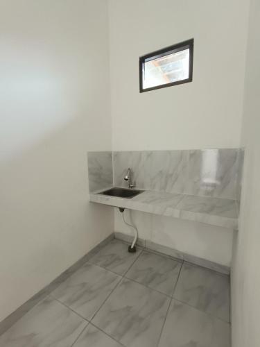 a bathroom with a sink in a white wall at Kamar Kost AC Mezanine in Gombong