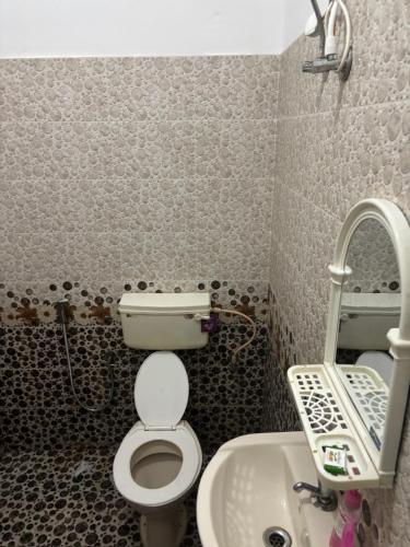a small bathroom with a toilet and a sink at Cozy Glick in Varkala
