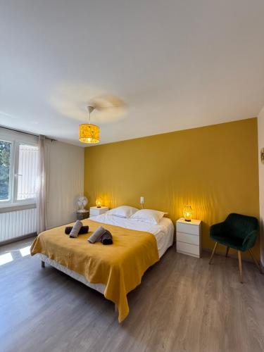 - une chambre avec un grand lit et un mur jaune dans l'établissement La Villa de Marius, à Arles