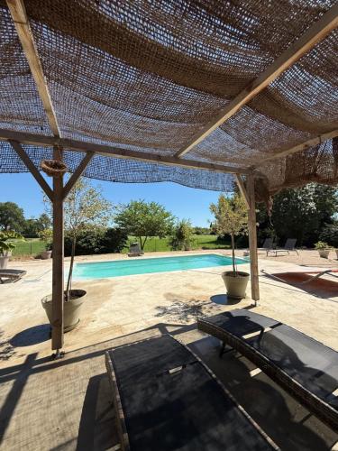 une pergola au-dessus d'une piscine avec un banc dans l'établissement La Villa de Marius, à Arles