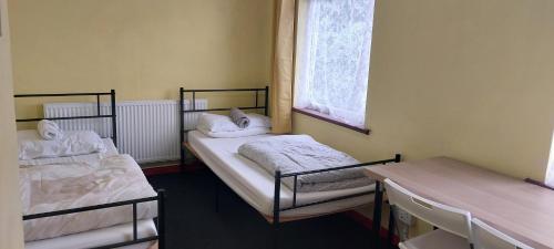a room with two beds and a table and a window at Linda 5BR House Of Basildon in Basildon