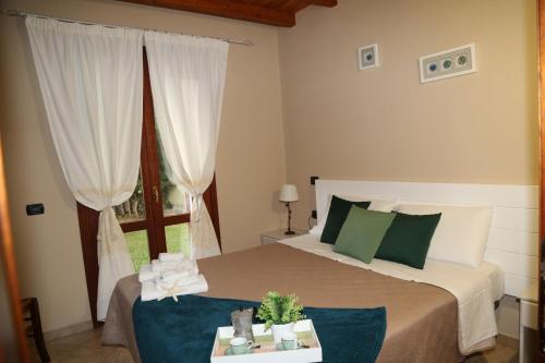 a bedroom with a bed with green pillows and a window at Villa Cruccuris in Villasimius