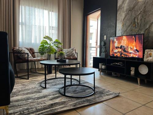 a living room with two tables and a flat screen tv at Lumi's Nest in Johannesburg