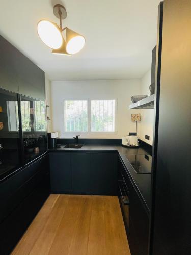 une cuisine avec des armoires noires et un ventilateur de plafond dans l'établissement Appartement T3 Mer Parking Conciergerie, à Bandol