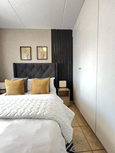 a bedroom with a large white bed with yellow pillows at Lumi's Nest in Johannesburg