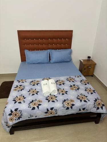 a bedroom with a bed with a blue comforter and two shoes at Cozy Glick in Varkala