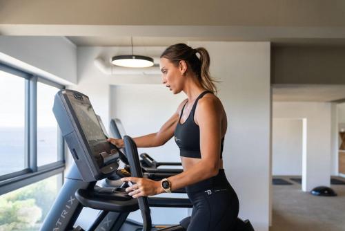 a woman running on a treadmill in a gym at Legend Hill Resort and Spa in Rivière Noire