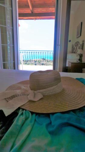 a straw hat on a bed with a view of the ocean at Fiore Hill Sea View Studios in Vasilikos