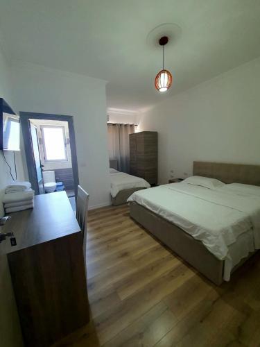 a bedroom with two beds and a desk in it at Kutal Park Inn Hotel in Përmet