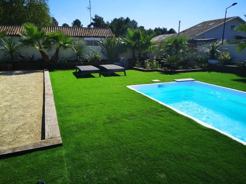 une cour avec une piscine et de l'herbe verte dans l'établissement Bassin d'Arcachon maison cozi, à La Celle-sous-Gouzon