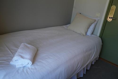 a white bed with a pillow and a towel on it at Norrqvarn Hotel & Resort by Vänerport in Lyrestad