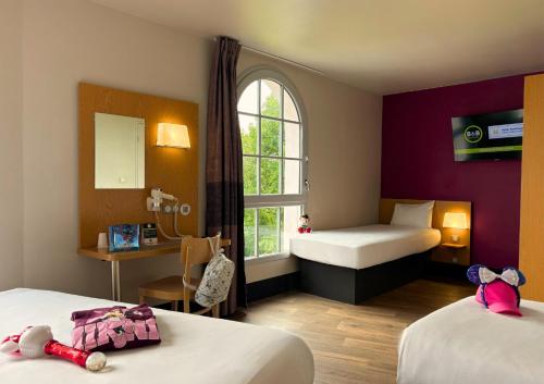 a hotel room with two beds and a window at B&B HOTEL près de Disneyland Paris in Magny-le-Hongre