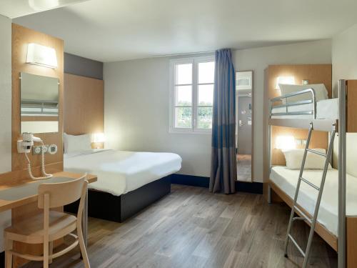a small room with two bunk beds and a desk at B&B HOTEL près de Disneyland Paris in Magny-le-Hongre
