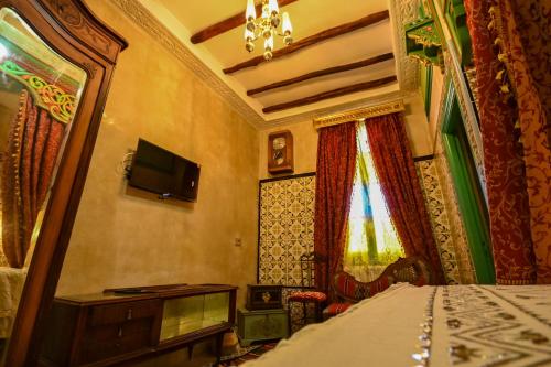 a bedroom with a bed with a television and a window at Dar KORAICH in Kairouan