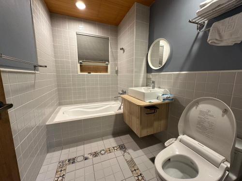 a bathroom with a tub and a toilet and a sink at 騎馬打仗民宿 in Yilan City