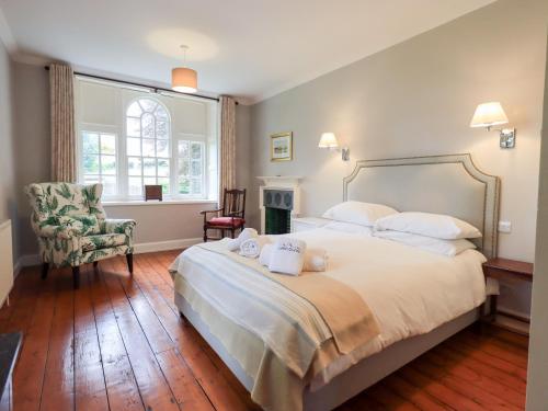 a bedroom with a large bed and a chair at Little Ellers in Portinscale