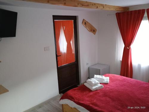 a bedroom with a red bed with towels on it at Casa FLOREA in Vama Buzăului
