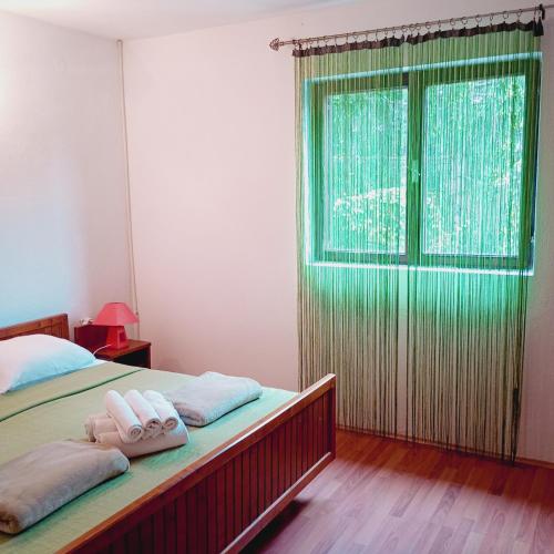 a bedroom with two towels on a bed with a window at Apartments with balcony and with large free parking House Oliver in Plitvička Jezera