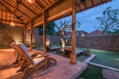 a wooden pavilion with two chairs on a patio at Villa Danginan & Dajanan Pemuteran in Pemuteran