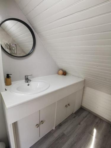 une salle de bain blanche avec un lavabo et un miroir dans l'établissement Chalet familial L'Abri Côtier, à Montmartin-sur-Mer