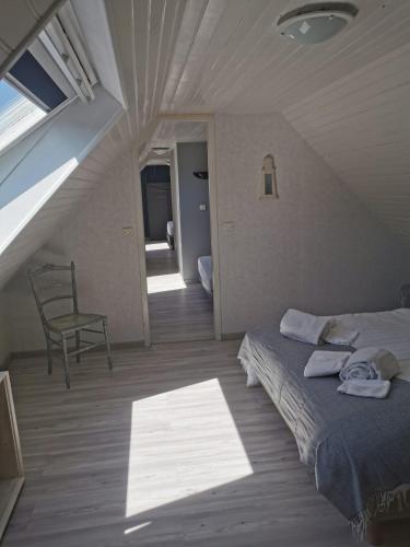 une chambre avec un lit et une chaise dans un grenier dans l'établissement Chalet familial L'Abri Côtier, à Montmartin-sur-Mer