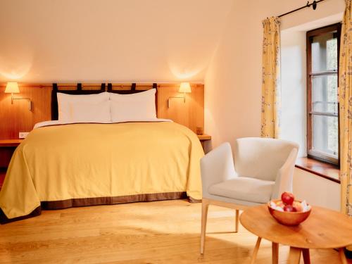 a bedroom with a bed and a chair and a table at TAUROA G'Schlössl Murtal in Großlobming