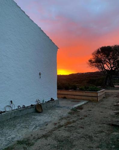 a sunset behind a white building with bikes parked against it at Stazzu Pittorra in Barrabisa