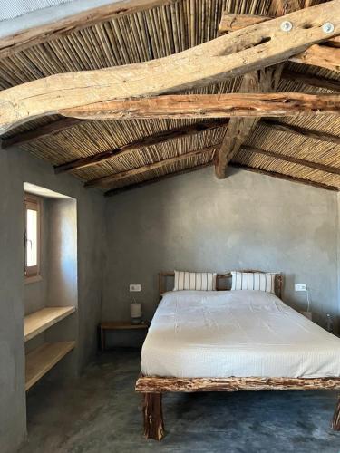 a bedroom with a large bed with wooden ceilings at Stazzu Pittorra in Barrabisa