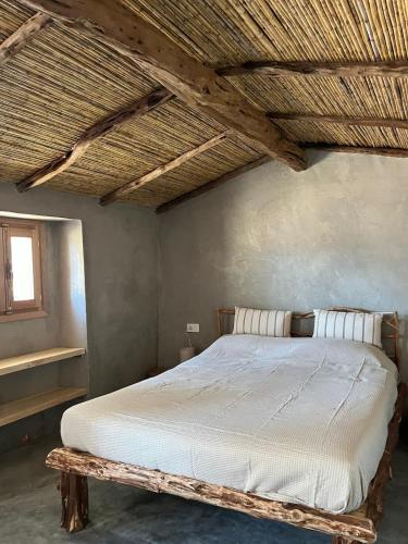 a bed in a bedroom with a wooden ceiling at Stazzu Pittorra in Barrabisa