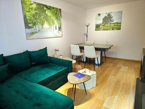 Una sala de estar con un sofá verde y una mesa. en Apartamentai 76, en Druskininkai