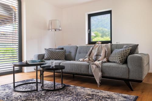 a living room with a gray couch and two tables at Vila Nina Bohinj in Bohinj