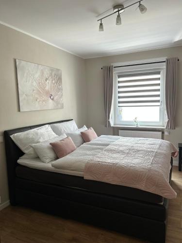 a bedroom with a bed with pink pillows and a window at WohnRaum Gäste- & Boardinghaus in Gusterath